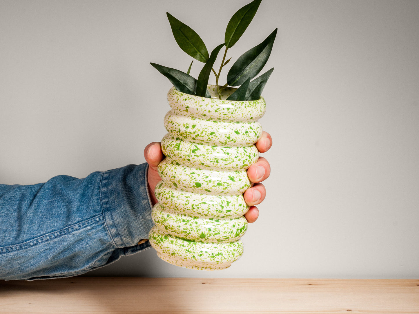 Green and white ceramic vase on wooden surface