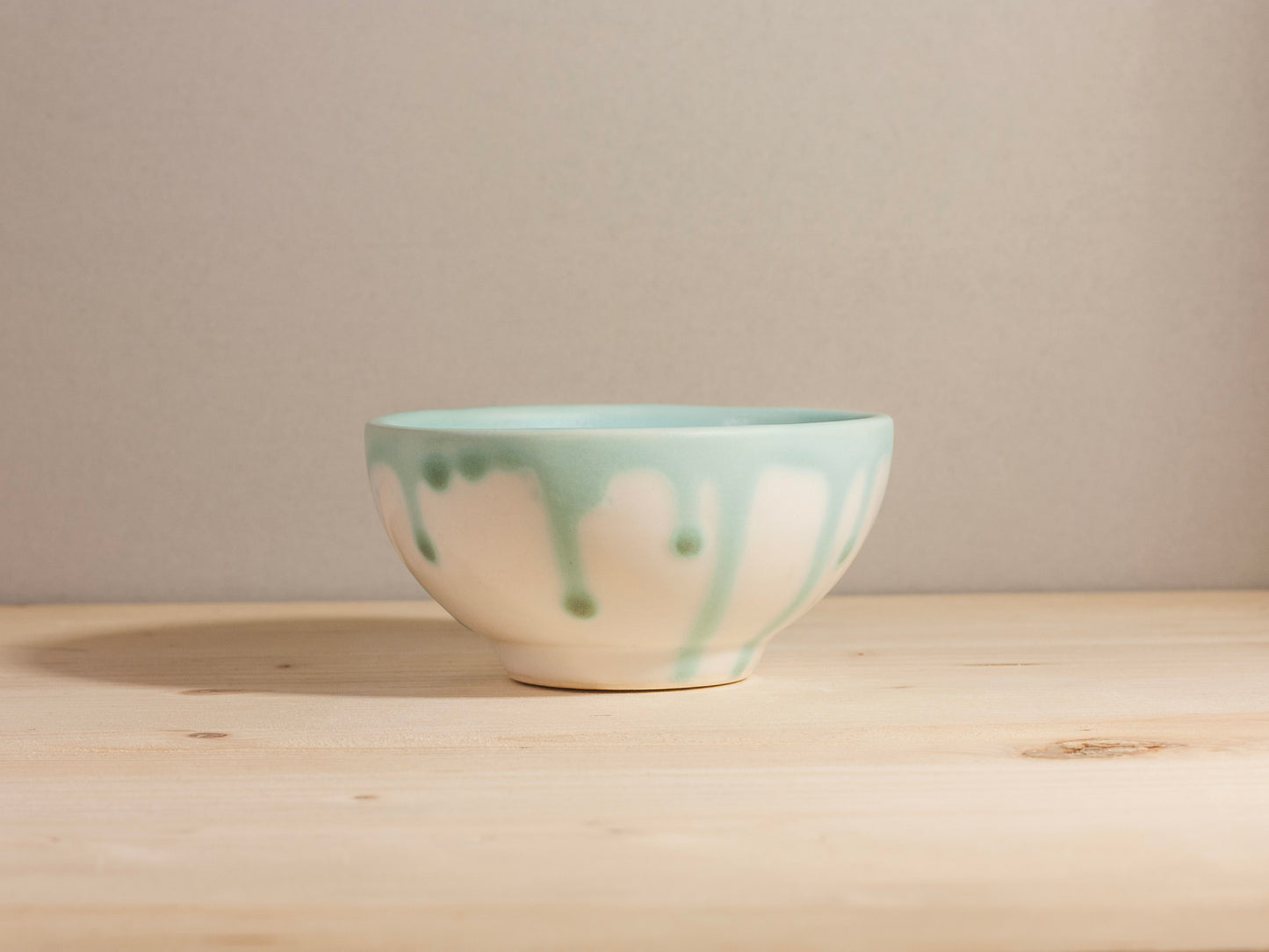 Ceramic bowl with green and white glaze on a wooden surface