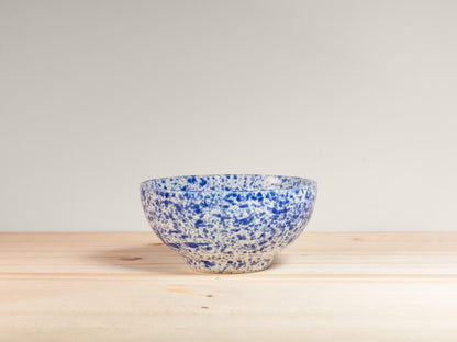 Blue and white ceramic bowl on a wooden surface with a light gray background