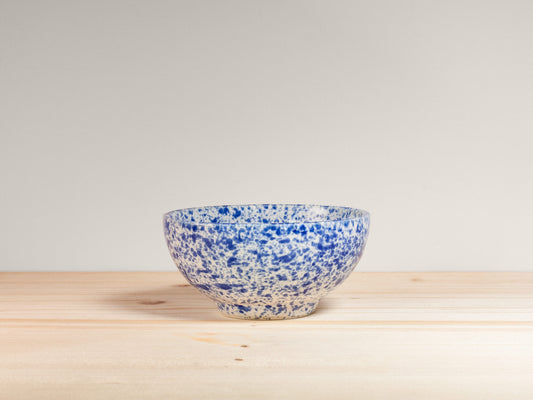 Blue and white ceramic bowl on a wooden surface with a light gray background