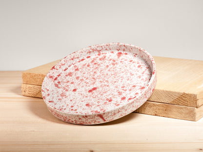 Speckled ceramic plate on a wooden surface with a light background
