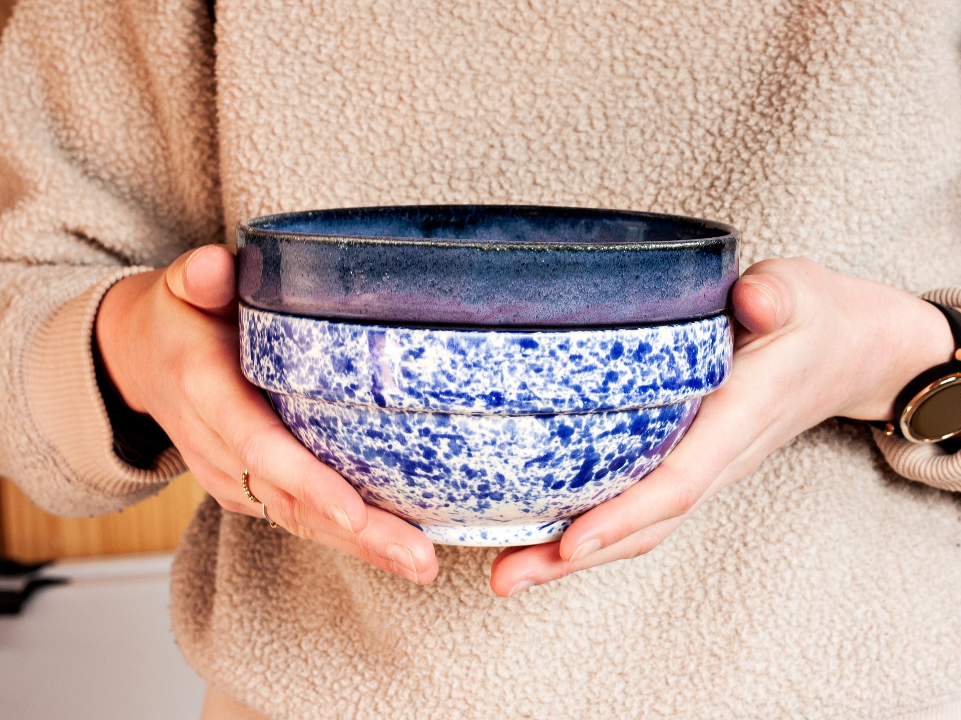 Person holding a blue and white speckled ceramic bowl