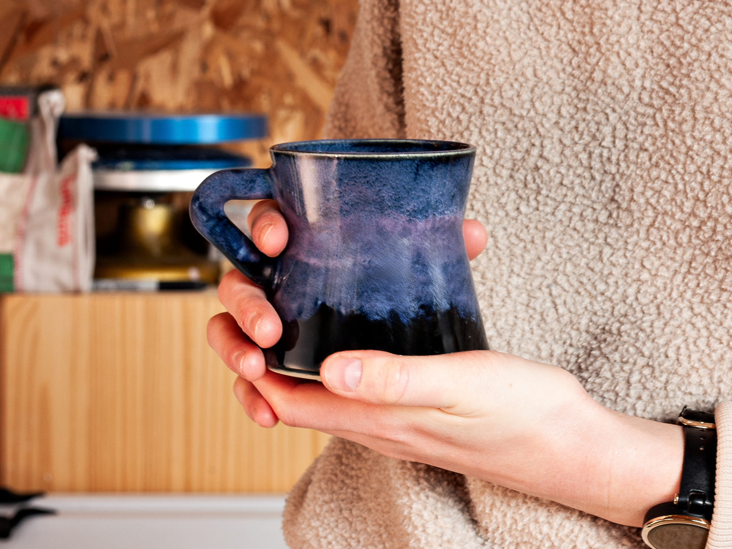 Person holding a blue mug in a workshop setting
