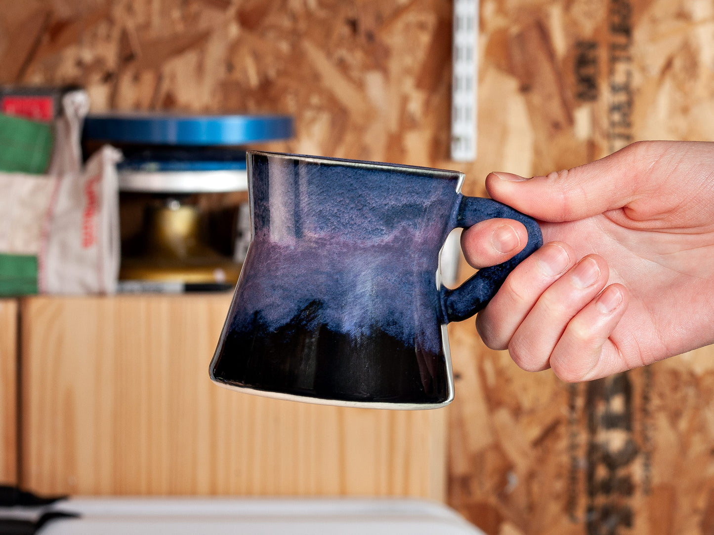 Hand holding a mug in a workshop setting