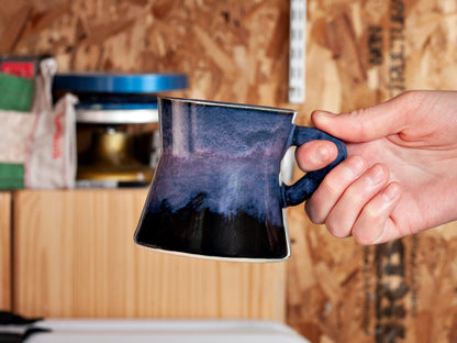 Hand holding a mug in a workshop setting
