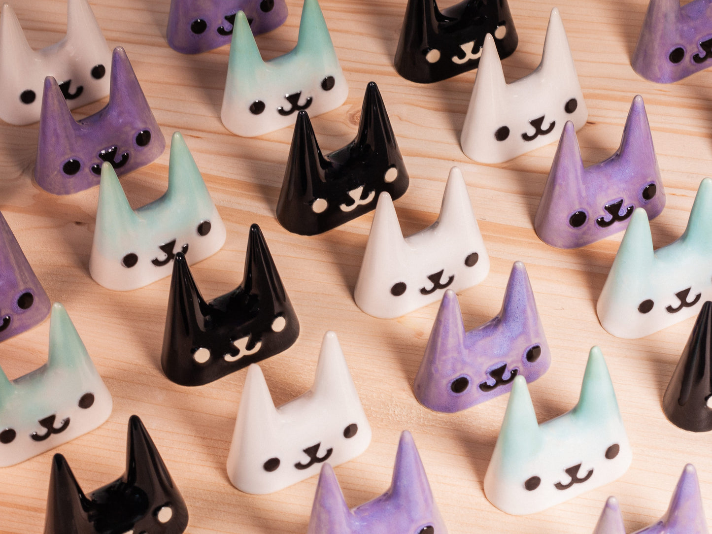 Set of ceramic ring holders with cat faces on a wooden surface