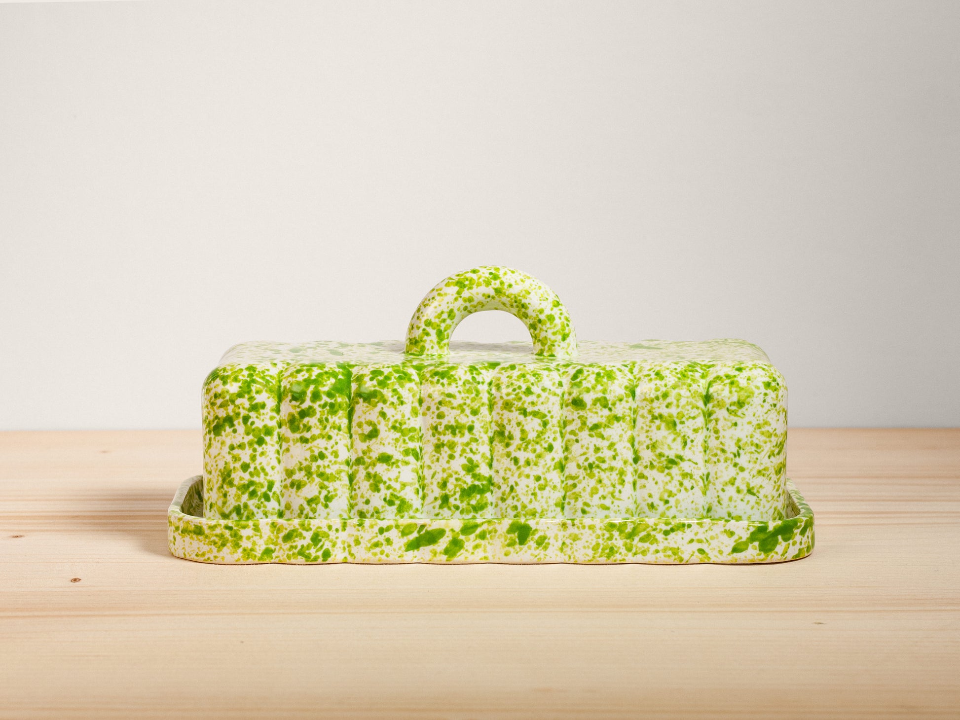 Green speckled butter dish on a wooden surface with a light background
