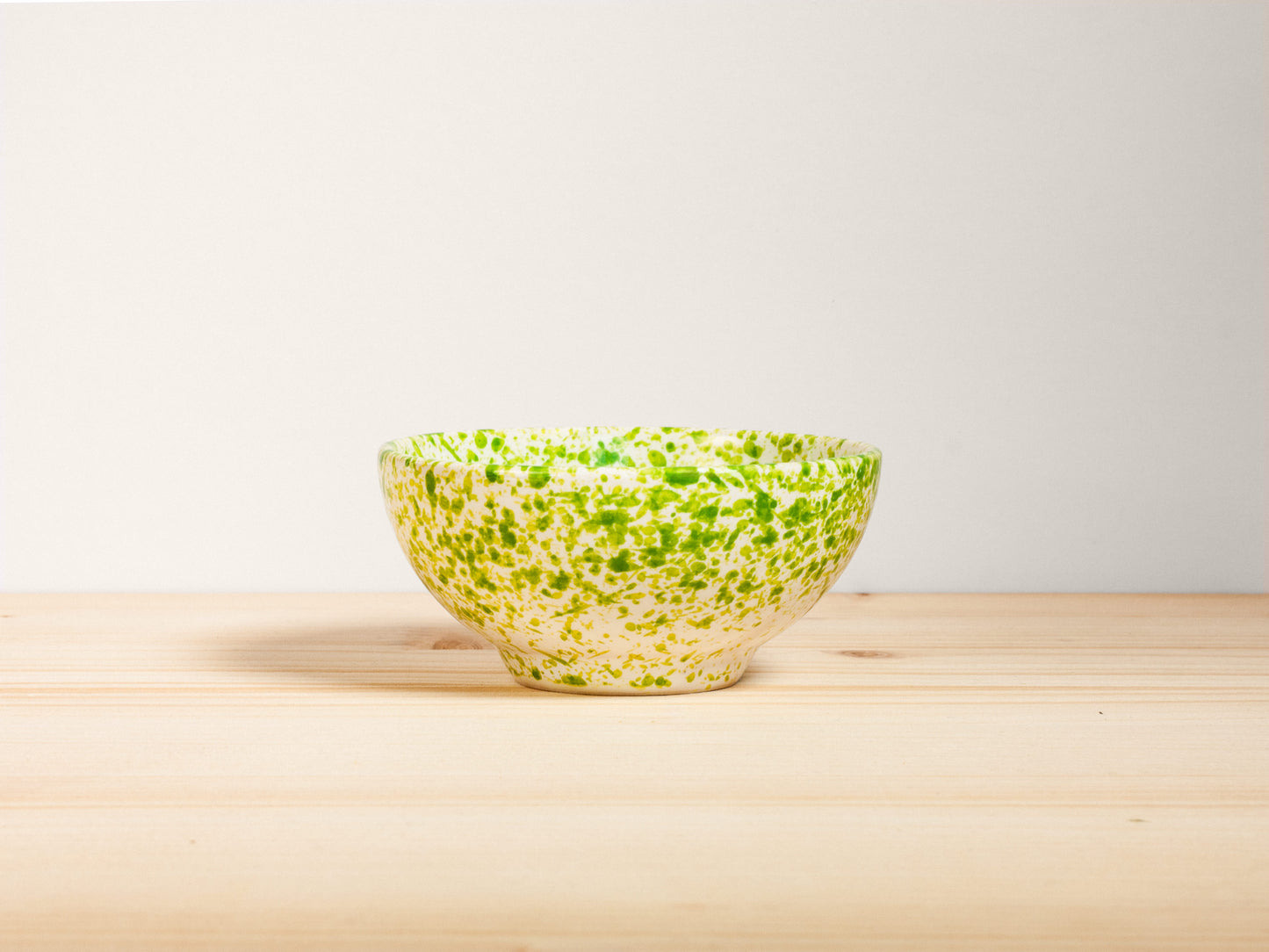 Green ceramic bowl on a wooden surface with a white background