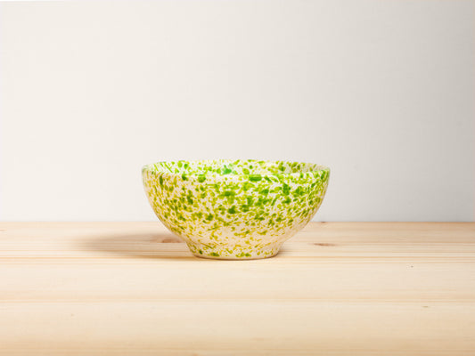Green ceramic bowl on a wooden surface with a white background