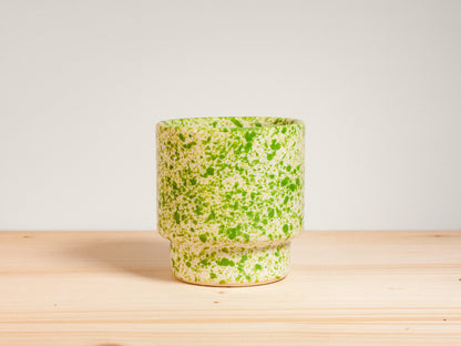 Green and white ceramic cup on wooden surface