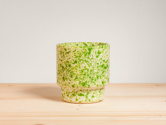 Green and white ceramic cup on wooden surface
