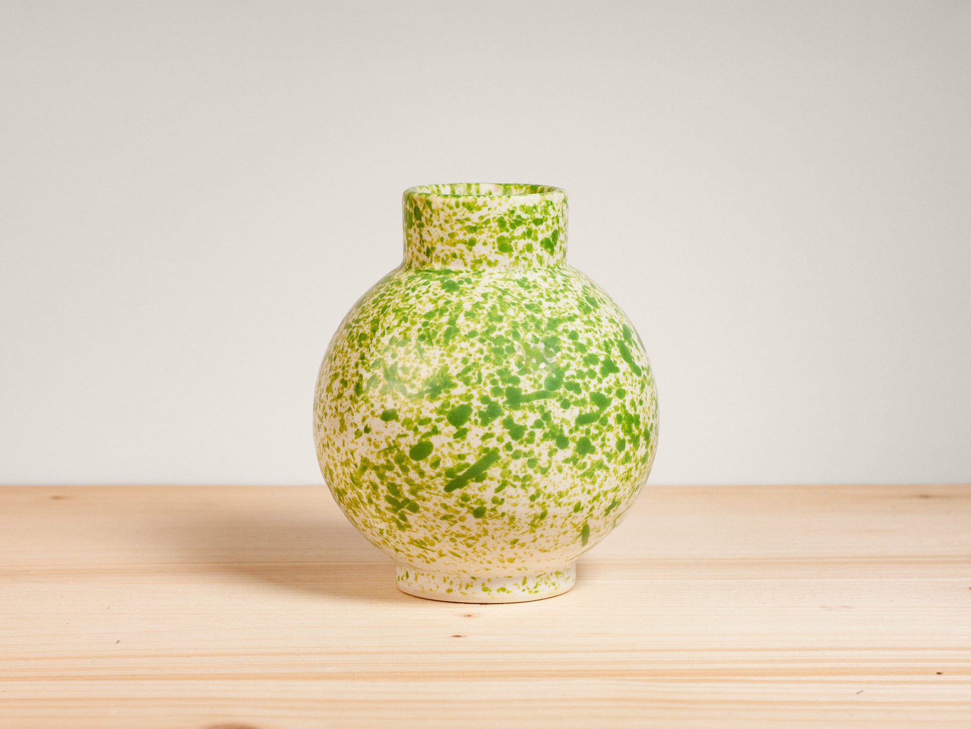 Green ceramic vase on wooden surface