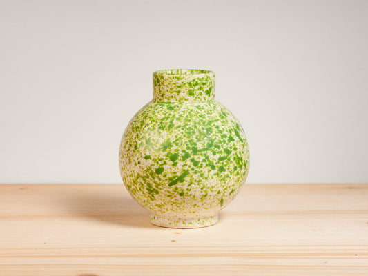 Green ceramic vase on wooden surface