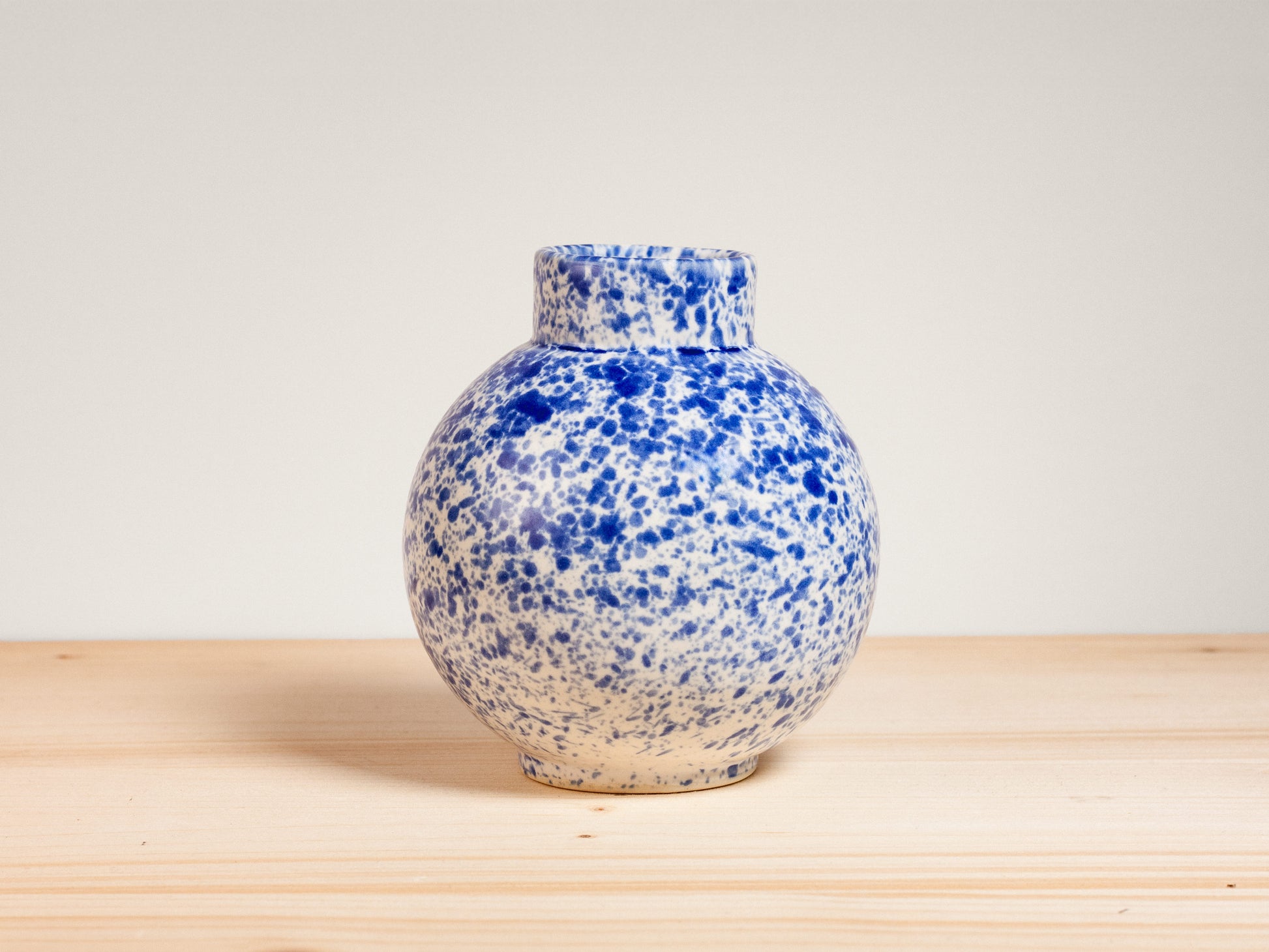 Blue and white ceramic vase on wooden surface with plain background