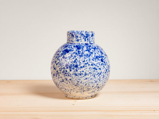 Blue and white ceramic vase on wooden surface with plain background