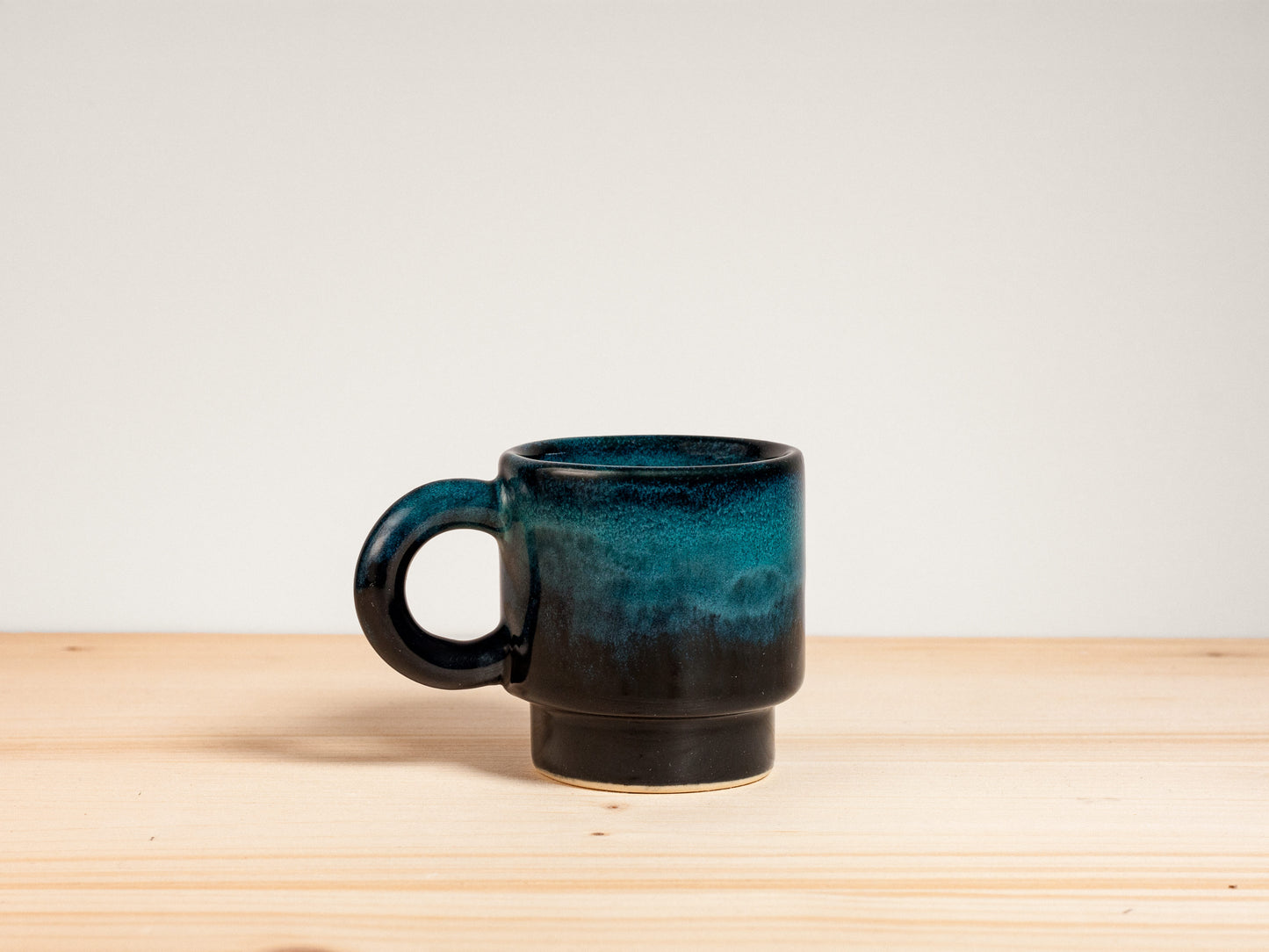 Dark teal ceramic espresso mug on wooden surface
