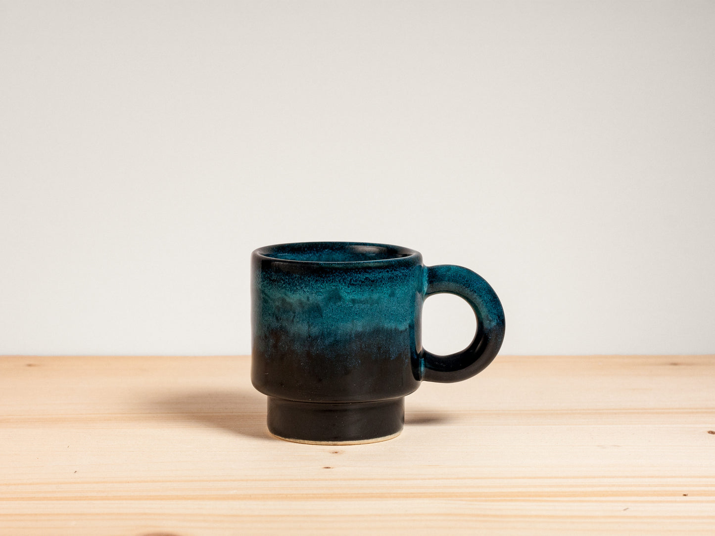 Dark teal ceramic espresso mug on wooden surface