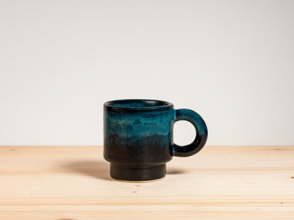 Dark teal ceramic espresso mug on wooden surface