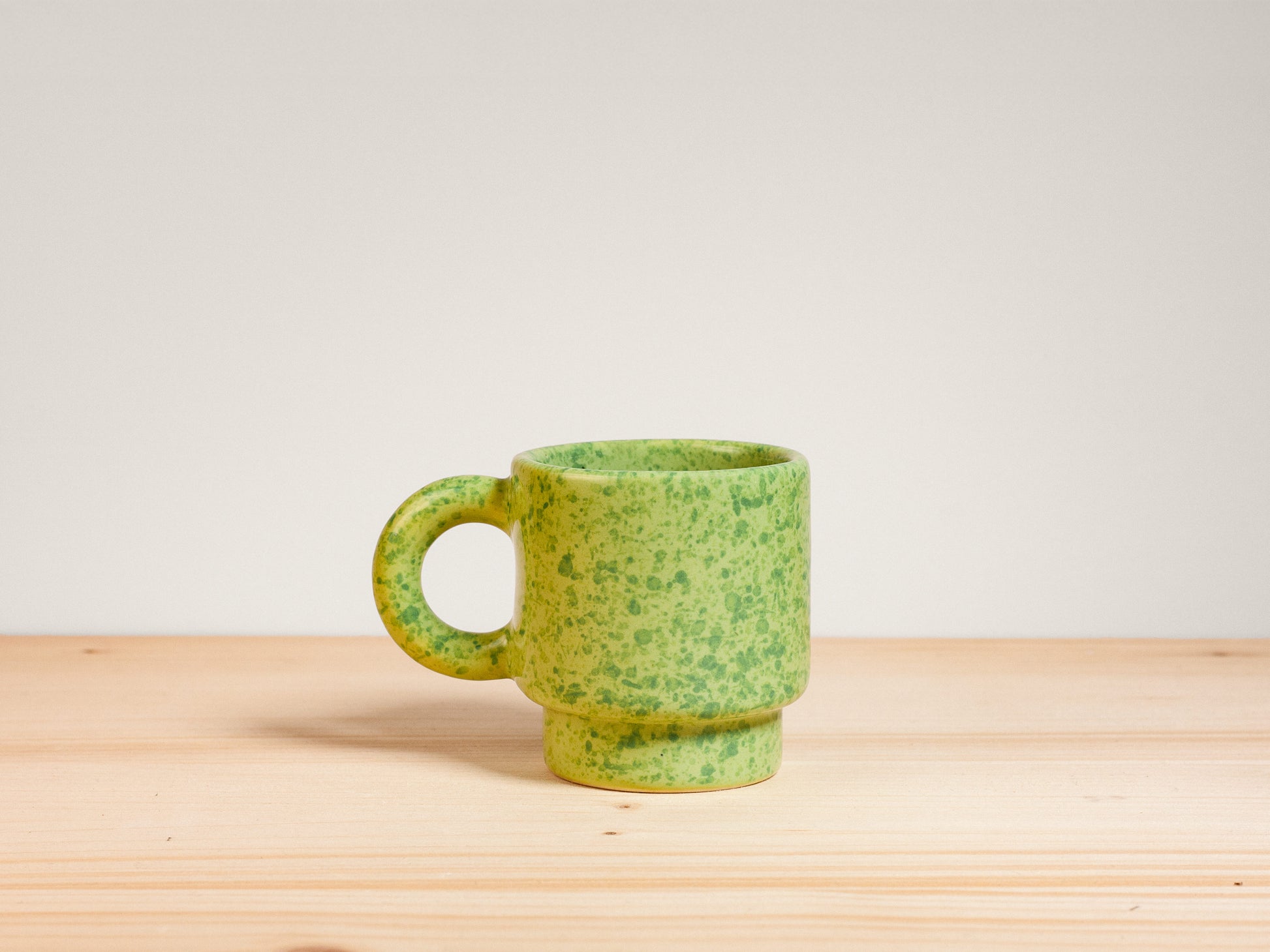 Green ceramic espresso mug on wooden surface