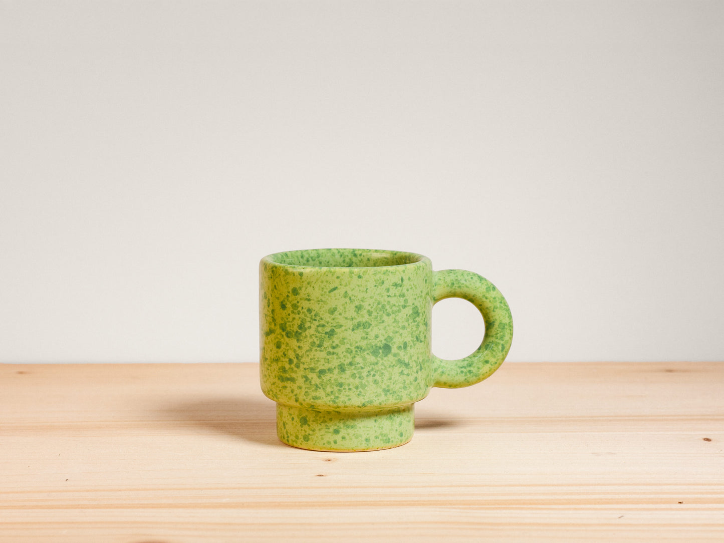 Green ceramic espresso mug on wooden surface