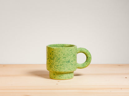 Green ceramic espresso mug on wooden surface