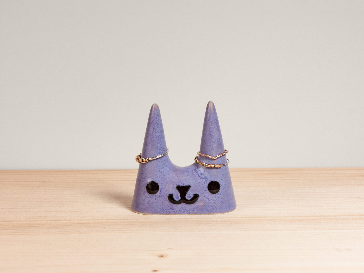 Purple cat-shaped ceramic ring holder on wooden surface