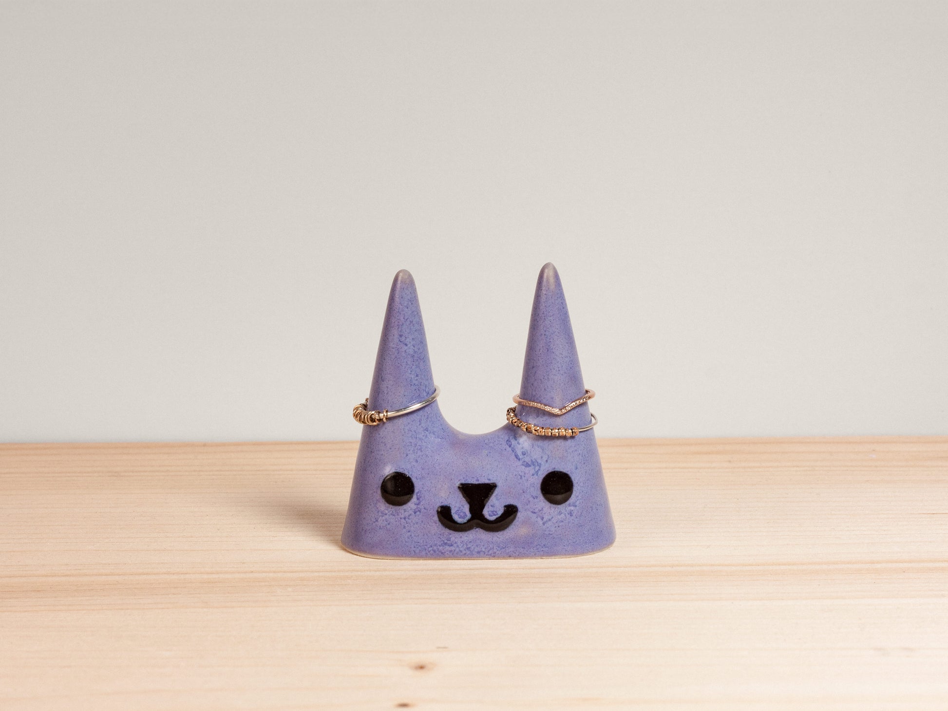 Purple cat-shaped ceramic ring holder on wooden surface