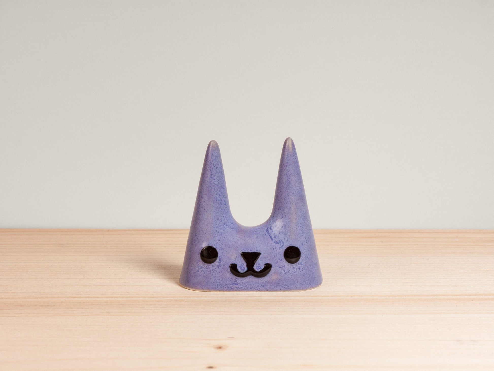 Purple cat-shaped ceramic ring holder on wooden surface
