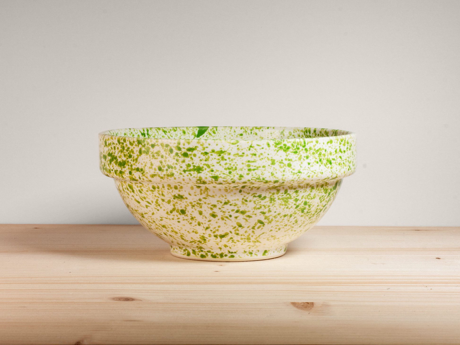 Green and white ceramic bowl on wooden surface