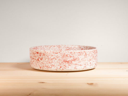 Pink and white ceramic bowl on a wooden surface with plain background