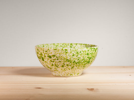 Green and white ceramic bowl on wooden surface