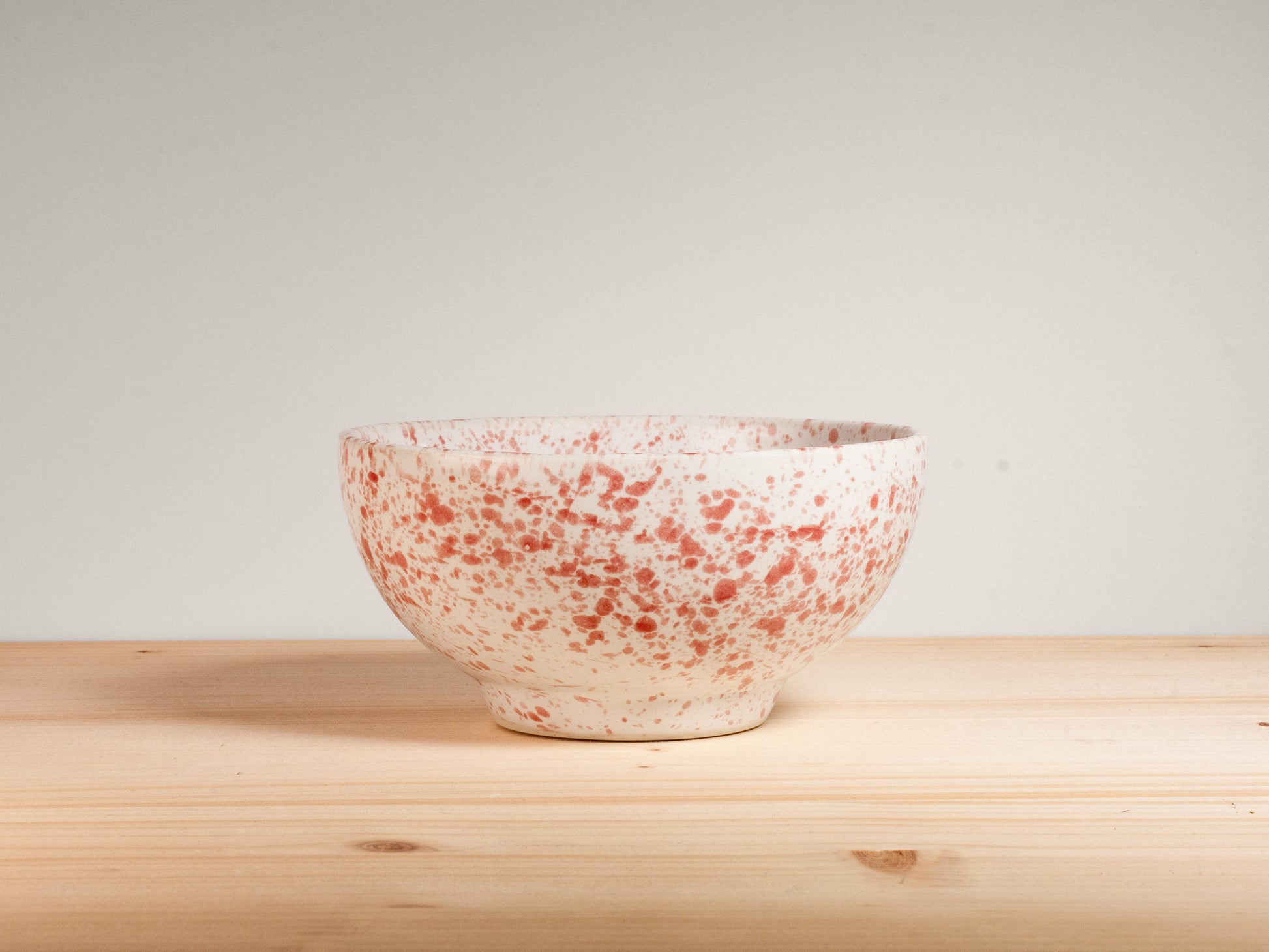 Pink and white ceramic bowl on wooden surface