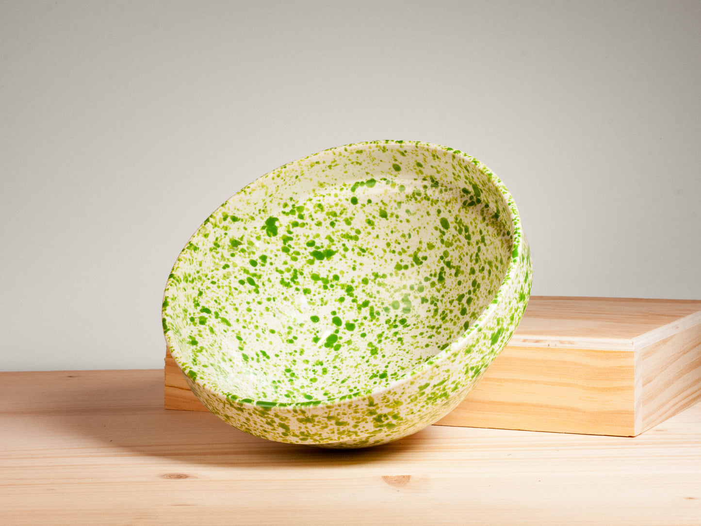 Green and white ceramic bowl on wooden surface