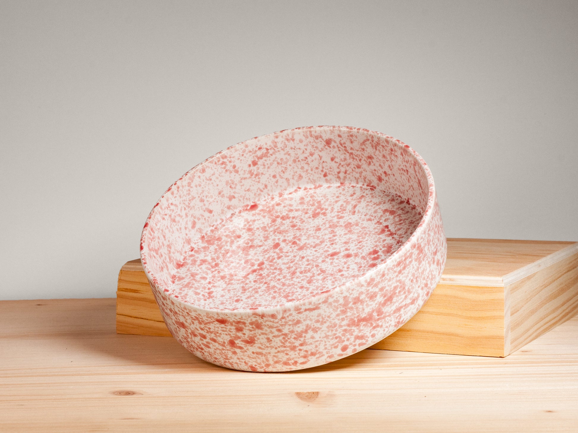 Pink and white ceramic bowl on a wooden surface with plain background