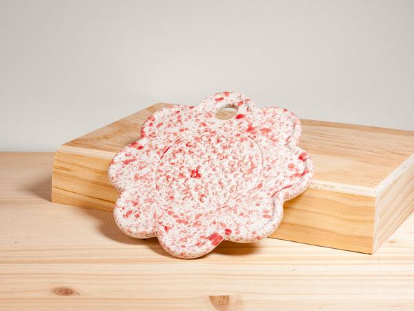Pink and white flower-shaped ceramic garlic grater on wooden surface