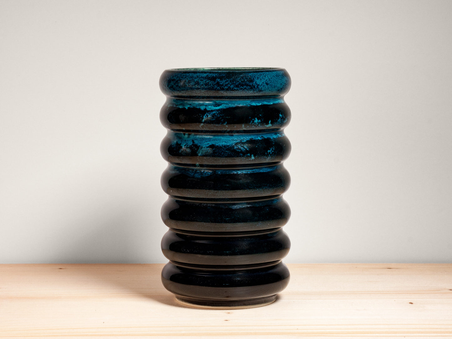 Dark teal ceramic vase on wooden surface