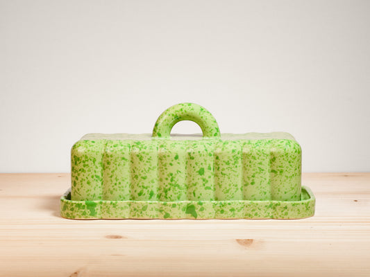 Green ceramic butter dish on wooden surface