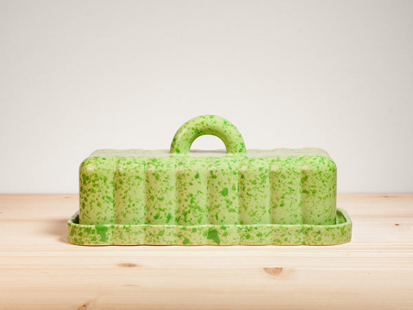 Green ceramic butter dish on wooden surface