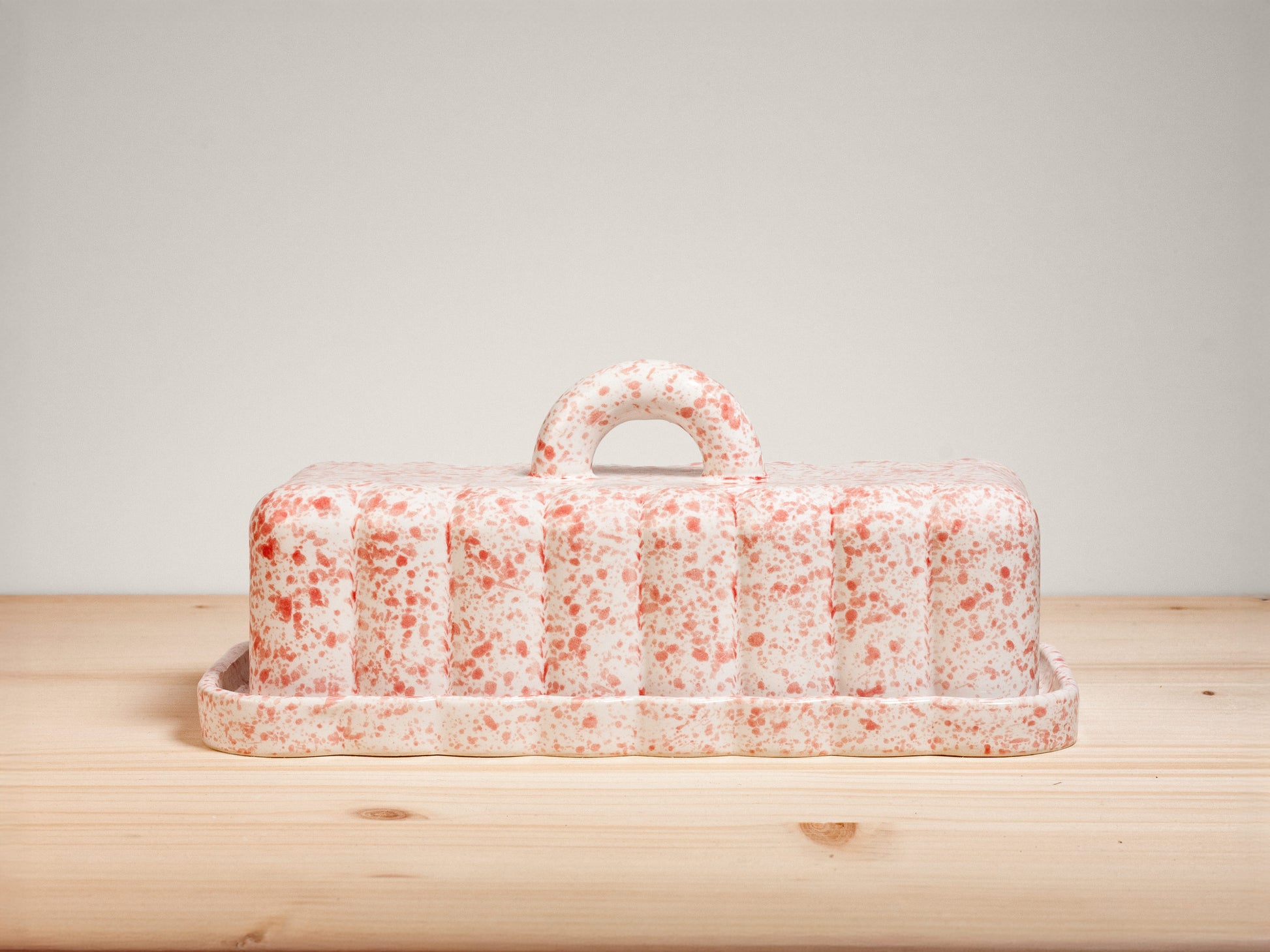 Pink and white ceramic butter dish on wooden surface