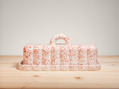 Pink and white ceramic butter dish on wooden surface