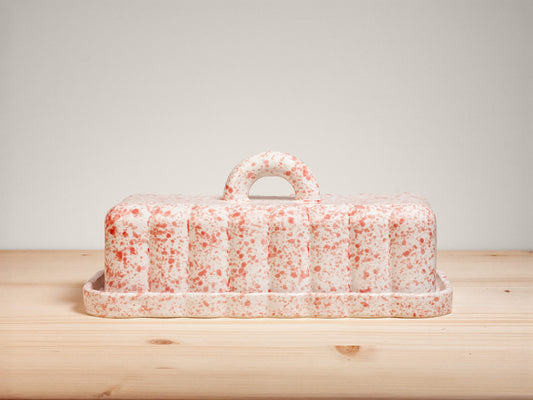 Pink and white ceramic butter dish on wooden surface
