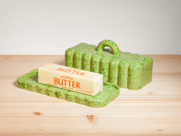 Green ceramic butter dish on wooden surface