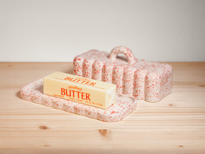 Pink and white ceramic butter dish on wooden surface