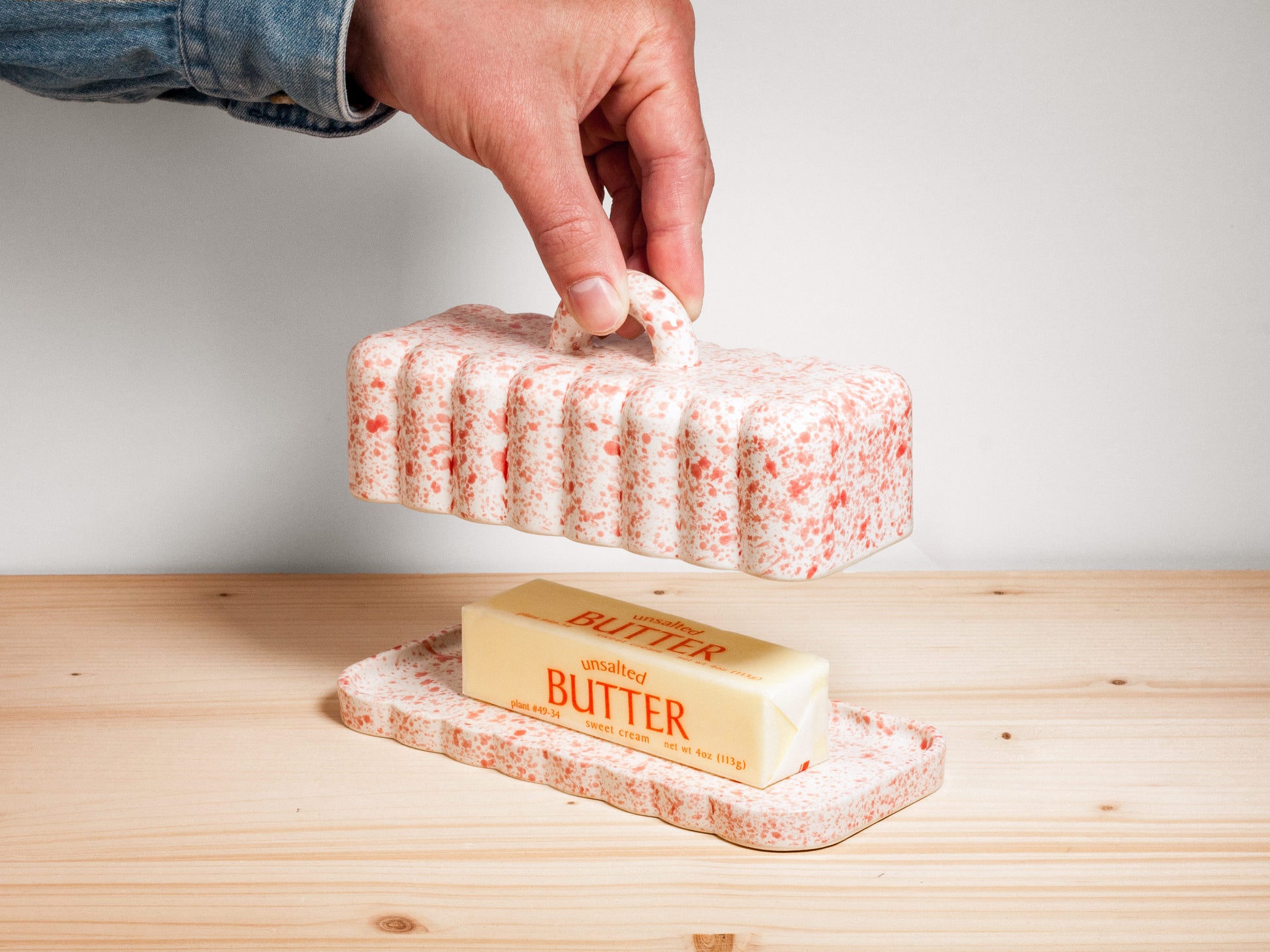 Pink and white ceramic butter dish on wooden surface