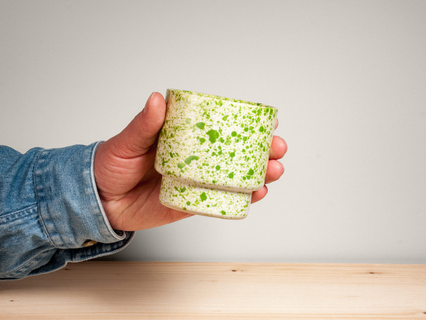 Green and white ceramic cup on wooden surface