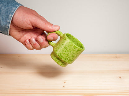 Green ceramic espresso mug on wooden surface