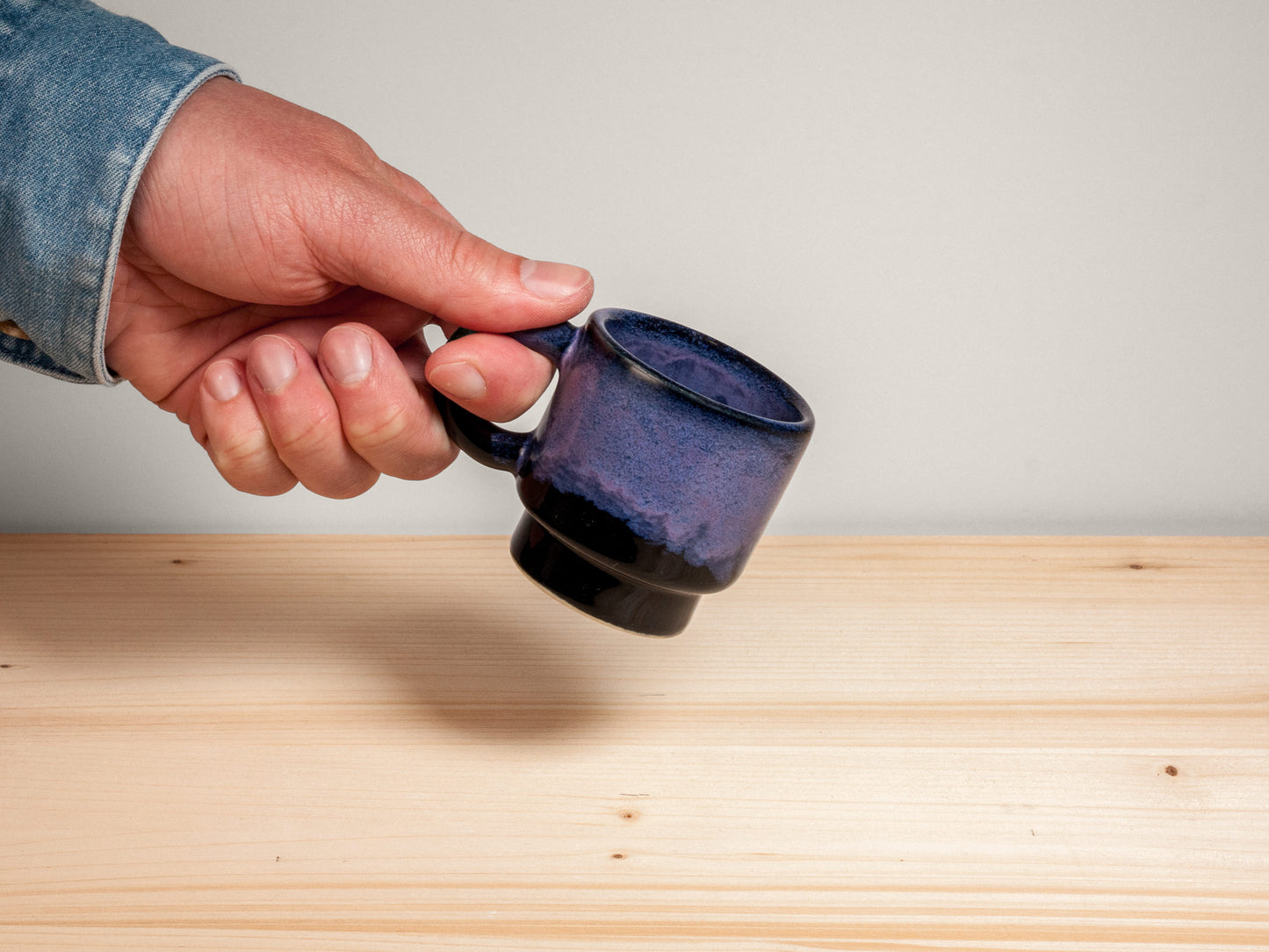 Hand holding dark purple espresso mug