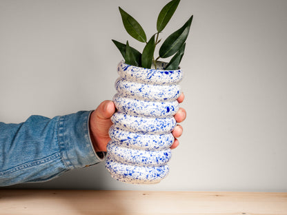 Hand holding blue and white ceramic vase on wooden surface