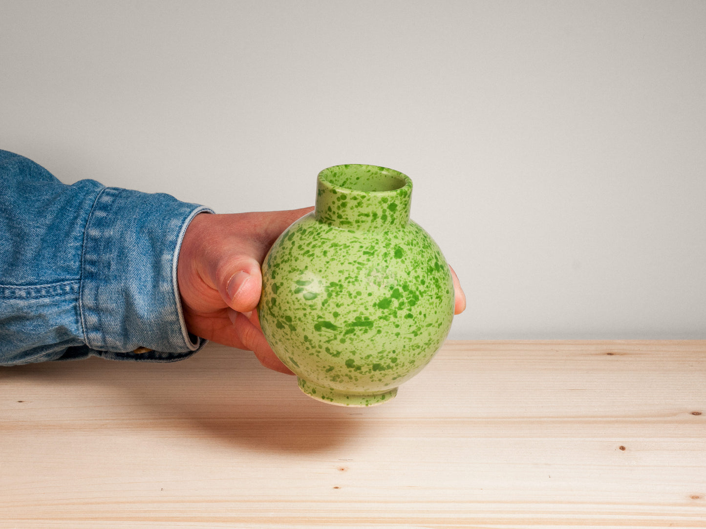 Green ceramic vase on wooden surface