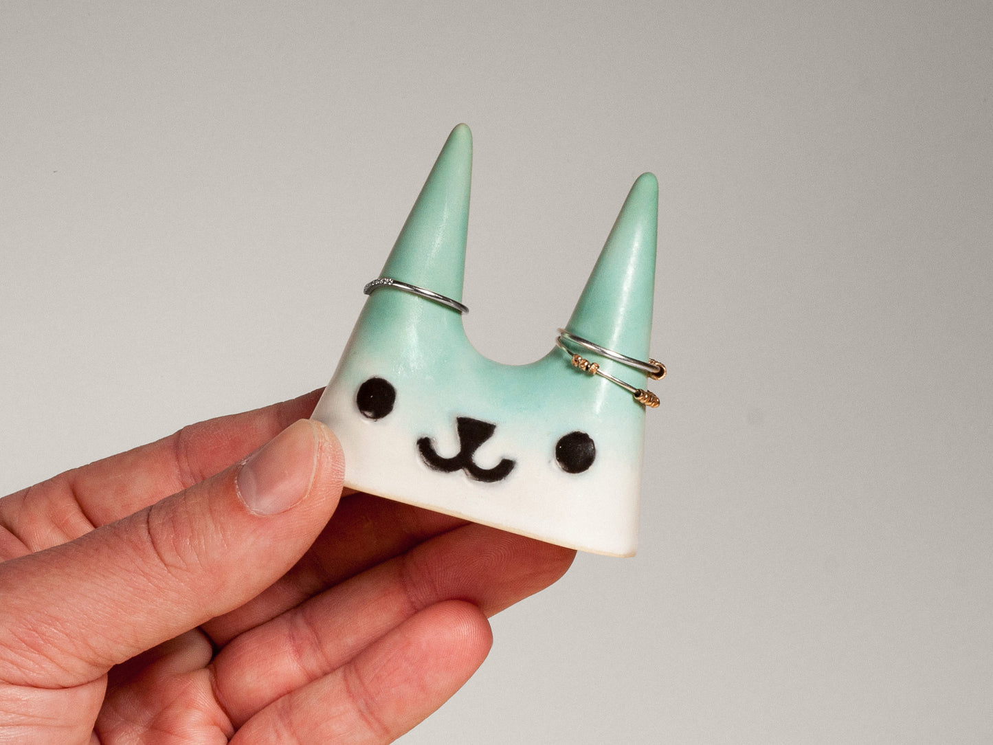 Hand holding a teal cat-shaped ceramic ring holder